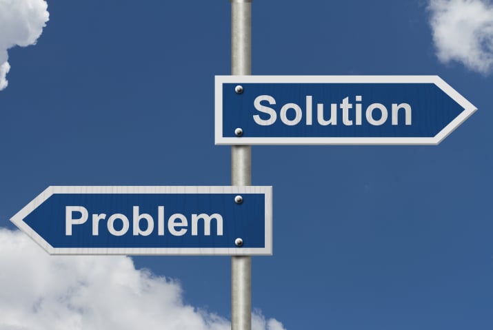 The image shows a signpost with two arrows pointing in opposite directions. The left arrow is labeled "Problem," and the right arrow is labeled "Solution." The sky is clear with a few scattered clouds in the background.