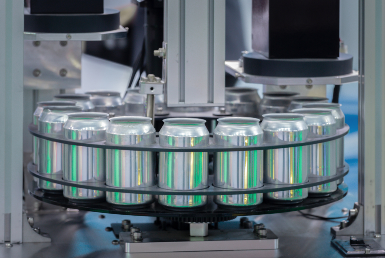 Automated food production line with aluminum cans in a manufacturing machine, highlighting the precision and efficiency of the process.